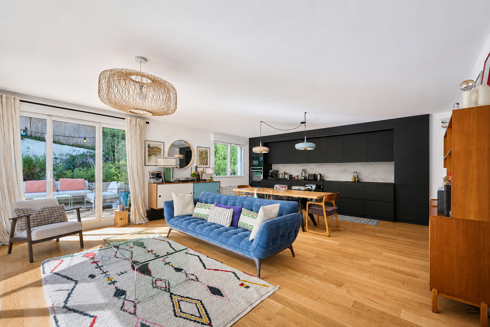 Séjour lumineux avec cuisine noire et canapé bleu photographié pour une annonce immobilière